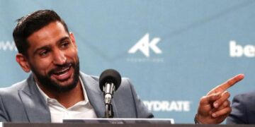 Amir Khan laughs and points his finger speaking at a news conference